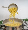 Cooking Pasta pour the penne pasta into a metal pot of boiling water. Boiled penne on a steel colander, in a cooking class Royalty Free Stock Photo