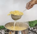 Cooking Pasta pour the penne pasta into a metal pot of boiling water. Boiled penne on a steel colander, in a cooking class Royalty Free Stock Photo