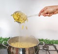 Cooking Pasta pour the penne pasta into a metal pot of boiling water. Boiled penne on a steel colander, in a cooking class Royalty Free Stock Photo