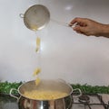 Cooking Pasta pour the penne pasta into a metal pot of boiling water. Boiled penne on a steel colander, in a cooking class Royalty Free Stock Photo