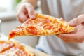 Cooking, people and food concept - close up of male hands taking slice of pepperoni pizza at home Royalty Free Stock Photo