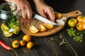 Cooking pickled vegetables in a jar. The cook cuts tomatoes with a knife on a cutting board in the kitchen. Close-up of chef hands Royalty Free Stock Photo