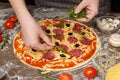 Cooking pizza. Woman adding rocket salad to pizza Royalty Free Stock Photo