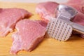Cooking pork meat chops. Raw slices of pork meat are beaten with a kitchen hammer on a wooden board before cooking. fresh raw meat Royalty Free Stock Photo