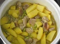 cooking pork meat, potatoes and green peas with onions in a pan at home