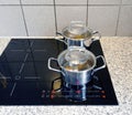 Cooking pots on a modern black glass-ceramic cooktop Royalty Free Stock Photo