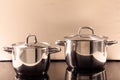 Cooking pots stainless placed on modern ceramic stove. Reflections, close up, details. Royalty Free Stock Photo