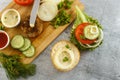 Cooking process of a sandwich burger, ingredients on wooden cutting board on wooden table against white background, fresh Royalty Free Stock Photo