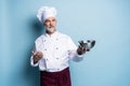 Cooking, profession and people concept - happy male chef cook holding bowl isolated on light blue.