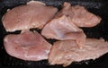 Cooking raw chicken fillets in a hot frying pan on stove, fresh meat on rustic grilling pan. Extreme close up real kitchen cooking