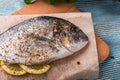 Cooking Raw Dorado Fish with Spinach, rosemary, olives, Herbs, Spices and Lemon closeup on Wooden Cutting Board on an aquamarine b Royalty Free Stock Photo