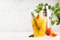 Cooking of refreshing juicy peach cocktail with ice, rosemary, sugar rim in misted glass, ingredients, silver shaker, green leaves