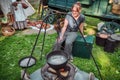 Cooking retro style in nature.. Woman sitting near the fire where the food is cooked