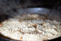 cooking Rice for pilaw or paella in iron cauldron over open fire. Smoke and steam. Tasty food preparing outdoor process background