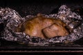 Cooking roasted whole chicken in foil in hot oven closeup. Juicy tender chicken with golden