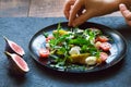 Cooking salad on a black plate. Arugula, cherry tomatoes, curd cheese, dark grapes, figs, thyme.