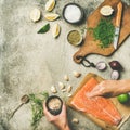 Female hands cooking salted salmon fish fillet on concrete table