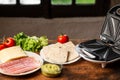 Cooking sandwiches in a sandwich maker. Different ingredients - bread, cheese, vegetables on a wooden background Royalty Free Stock Photo