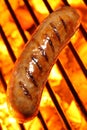 Cooking a sausage hot dog on barbecue grill