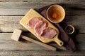 Cooking schnitzel. Raw pork slices, egg, peppercorns and meat tenderizer on wooden table, flat lay Royalty Free Stock Photo