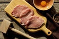 Cooking schnitzel. Raw pork slices, egg, peppercorns and meat tenderizer on table, flat lay Royalty Free Stock Photo