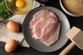 Cooking schnitzel. Raw pork slices, other ingredients and meat tenderizer on wooden table, flat lay Royalty Free Stock Photo