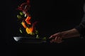 Cooking seafood, frying in a pan with vegetables, veggie healthy food, on a black background, menu and restaurant business