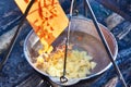 Cooking soup in the stowed bowler over campfire Royalty Free Stock Photo