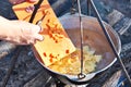 Cooking soup in the stowed bowler over campfire Royalty Free Stock Photo