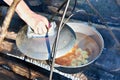 Cooking soup in the stowed bowler over campfire Royalty Free Stock Photo