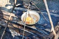 Cooking soup in the stowed bowler over campfire Royalty Free Stock Photo