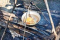 Cooking soup in the stowed bowler over campfire Royalty Free Stock Photo