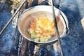 Cooking soup in the stowed bowler over campfire Royalty Free Stock Photo