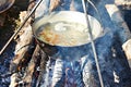 Cooking soup in the stowed bowler over campfire Royalty Free Stock Photo