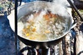 Cooking soup in the stowed bowler over campfire Royalty Free Stock Photo