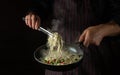 Cooking spaghetti with spices and seasonings in a pan by the hands of an experienced chef. Recipe or menu for a restaurant or cafe Royalty Free Stock Photo