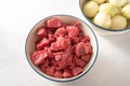 Cooking stew or goulash with diced beef and al lot of peeled onions, these two ingredients in bowls from above on a white table