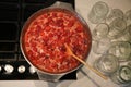 Cooking strawberry jam in a large bowl at home. Wooden spoon in a bowl with jam. Empty glass jars for jam. Royalty Free Stock Photo