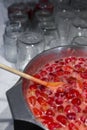 Cooking strawberry jam in a large bowl at home. Wooden spoon in a bowl with jam. Empty glass jars for jam. Royalty Free Stock Photo