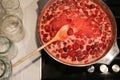 Cooking strawberry jam in a large bowl at home. Wooden spoon in a bowl with jam. Empty glass jars for jam. Royalty Free Stock Photo