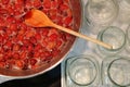 Cooking strawberry jam in a large bowl at home. Wooden spoon in a bowl with jam. Empty glass jars for jam. Royalty Free Stock Photo