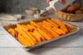 Cooking sweet potato wedges, fries on a baking pan. Hand adding oil. Royalty Free Stock Photo