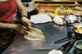 Cooking sweet Thai pancakes. A female cook on the street rolls and turns the dough, close-up of the hand. traditional Royalty Free Stock Photo