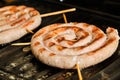 Cooking white spiral sausages on grill Royalty Free Stock Photo