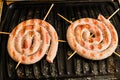 Cooking white spiral sausages on grill Royalty Free Stock Photo