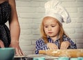 Cooking training. Child cook in chef hat helping mother Royalty Free Stock Photo