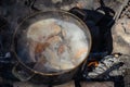 Cooking ukha on the campfire. Cast-iron cauldron with boiling fi