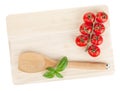 Cooking utensil and tomato with basil over cutting board