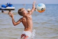 Cool sports boy jumping on the ball at sea