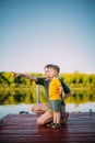 Cool baby boy with mother looking on river standing on pier. Summer photography for blog or ad about family and travel